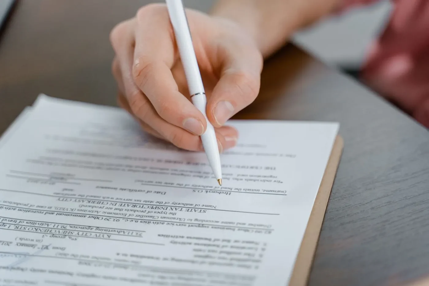 Pessoa assinando um documento sobre a mesa