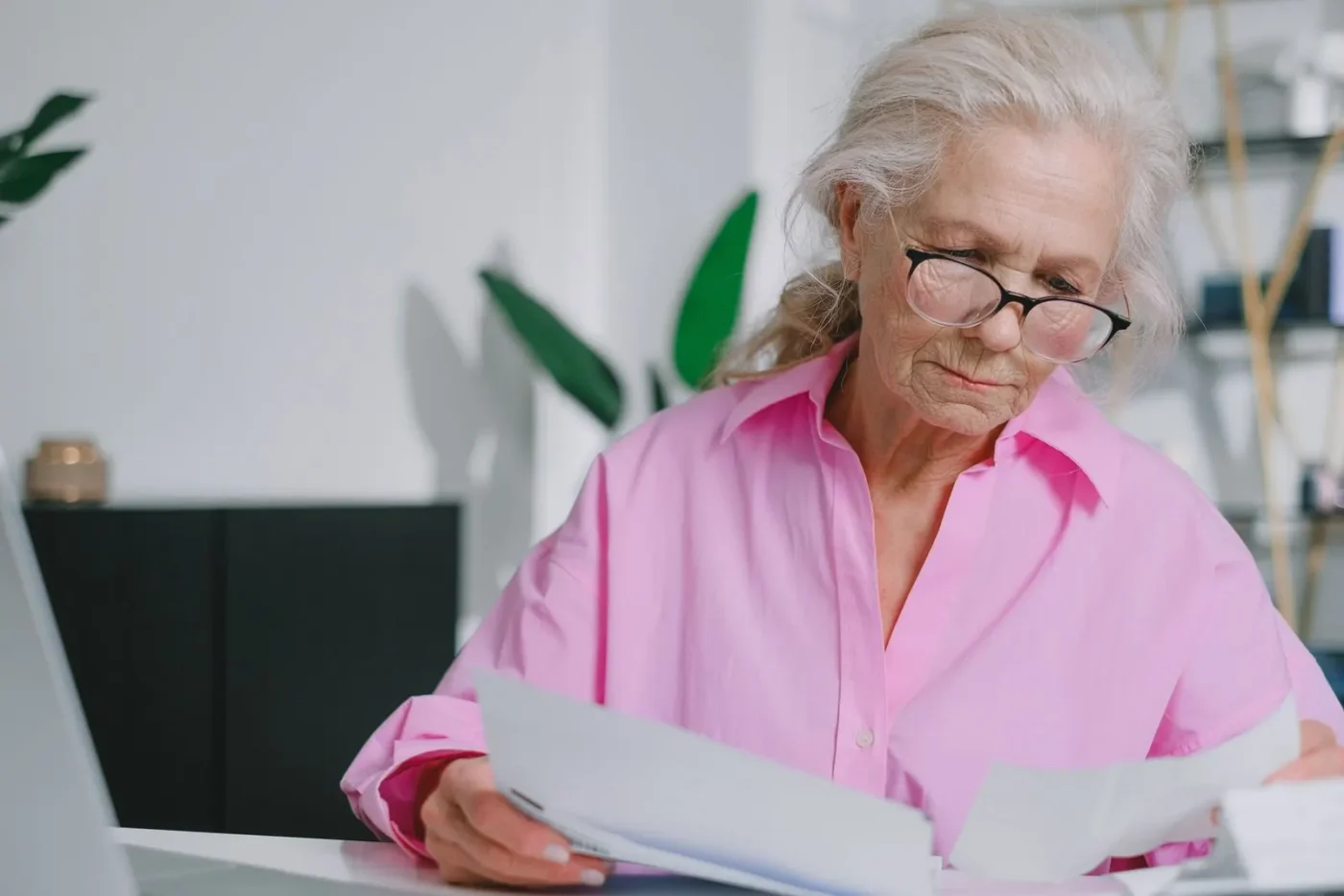 Senhora de óculos lendo documentos à mesa