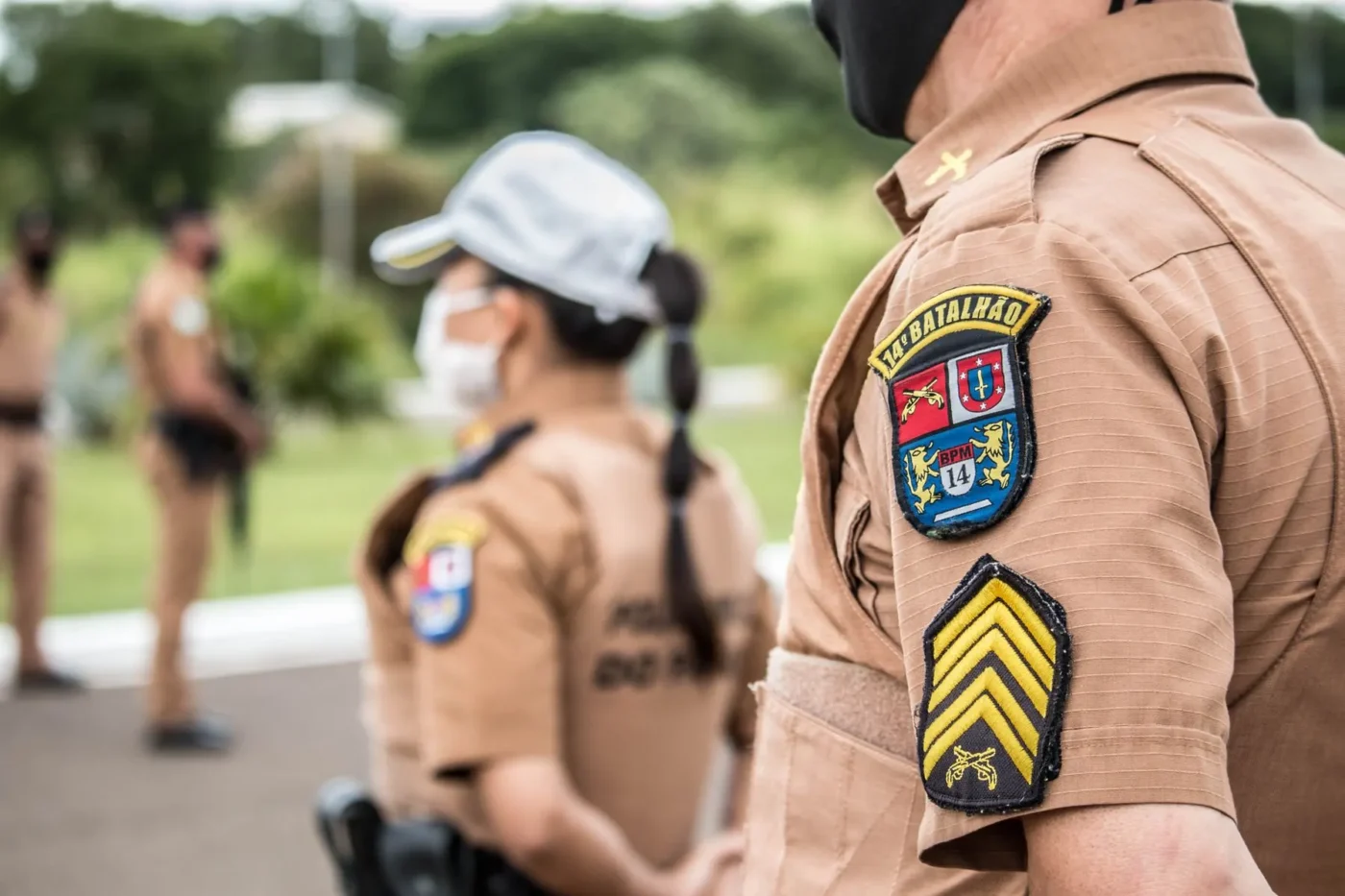 Policiais militares fardados conversando em área externa